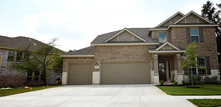 Brick Eagle House with two garages, landscaped lawn, and a wide driveway offered by TDY Haven Crash Pad in Schertz, TX